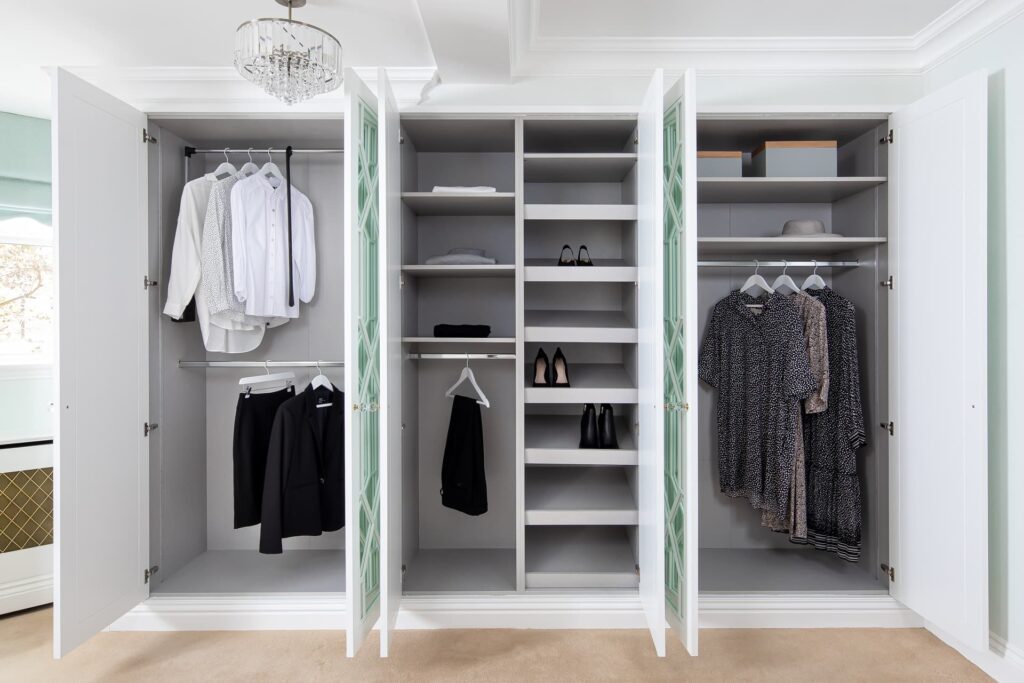 A white cabinet with three hanging rails, shelves, and shoe storage