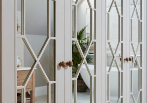 Mirrored Hampton style fitted wardrobes in white, reflecting batchtub in morroed doors
