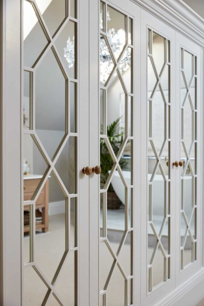 Mirrored Hampton style fitted wardrobes in white, reflecting batchtub in morroed doors