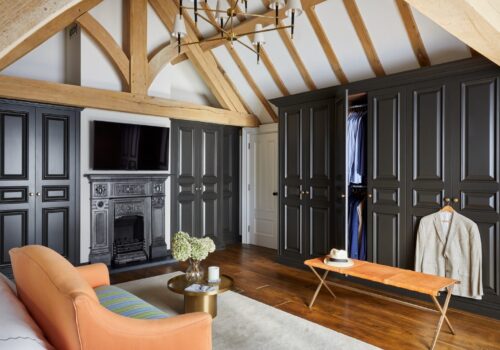 bespoke-wardrobes-tudor-002 Monochromatic dressing room with lively accents: vibrant chair, couch, and decorative vase for added character