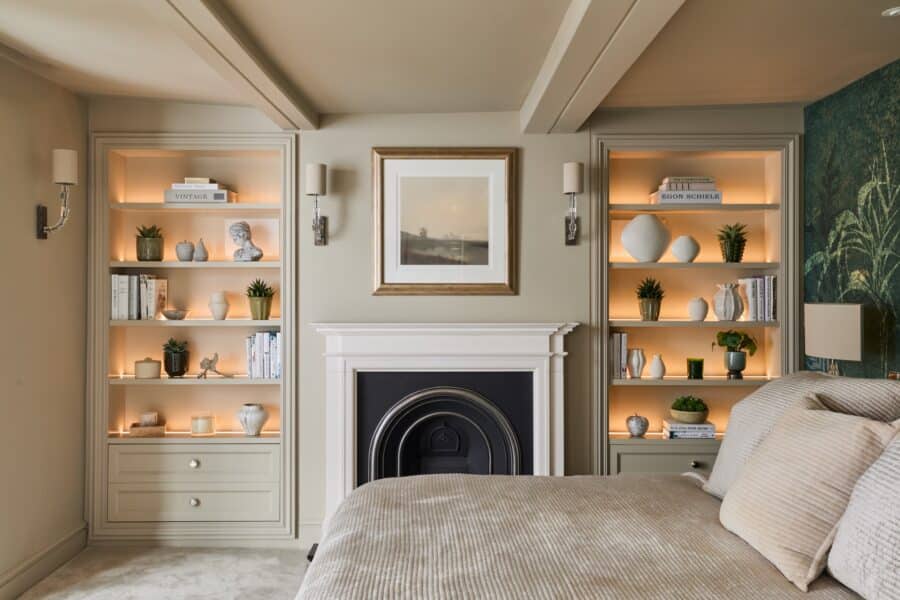 Matching Victorian style built-in shelving either side of fireplace in a bedroom - with light on